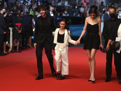 Ben, Alice, and Jo Attal are holding hands as they are walking in the red carpet.